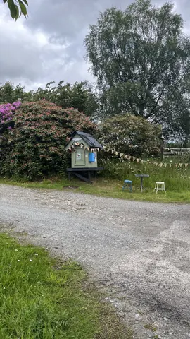 A small house is sitting in the middle of a field.