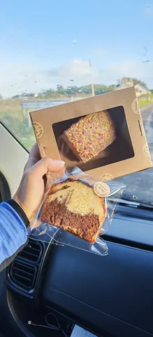 A person is holding a box of cake and a cake in their hand.