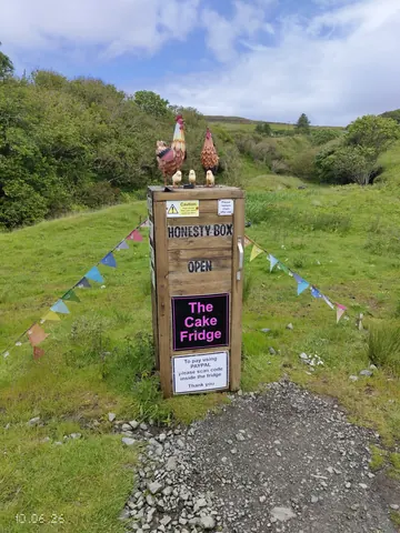 A sign for a cake fridge is on a wooden post.