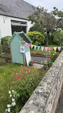 A small blue shed with a sign on it.
