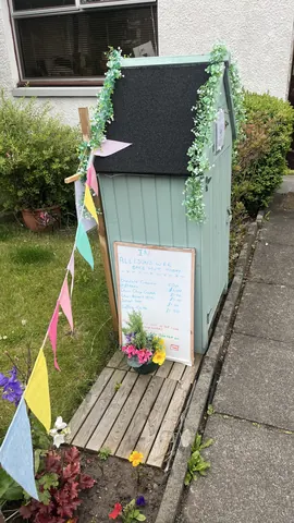 A small green shed with a sign on it.