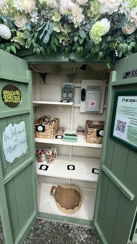 A small green building with a shelf inside.