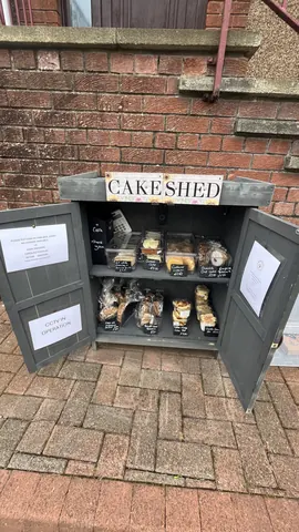A small wooden box with a sign that says "Cake Shed" on it.