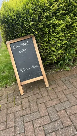 A sign that says "Cake Shed Open" is on a sidewalk.