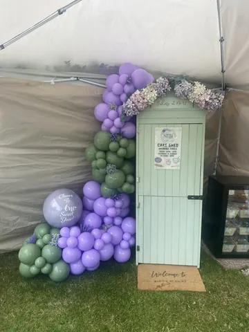 A white shed with a purple balloon on top of it.