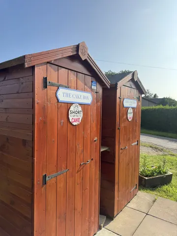 Two wooden outhouses with signs on them.