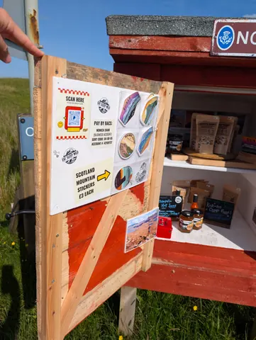 A sign with stickers on it is displayed on a wooden frame.