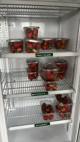 A refrigerator with strawberries in plastic containers.