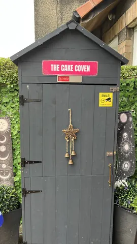 A small building with a sign that says "The Cake Coven" on it.