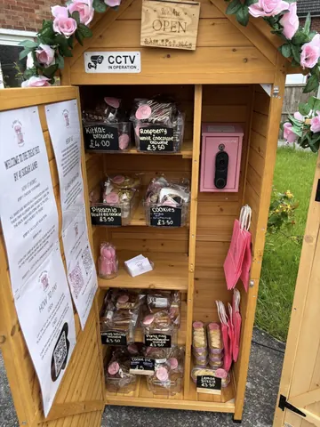 A wooden box with a pink door and a sign that says "welcome to our bakery".
