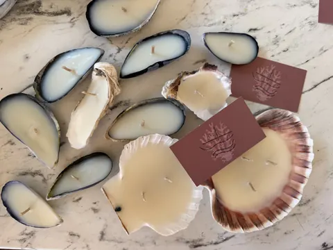 A collection of candles and shells on a table.