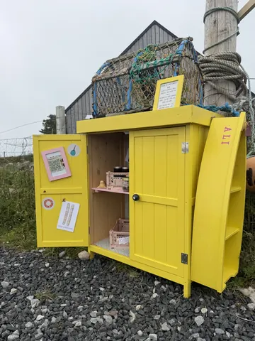 A yellow building with a pink door and a sign on the door.