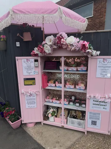 A pink and white food stand with a pink umbrella.