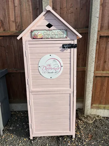 A pink shed with a white sign on it.
