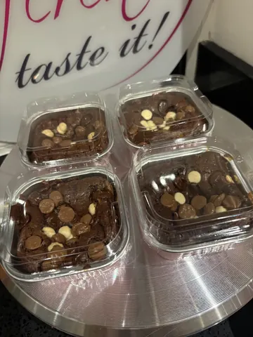 A plate with four containers of chocolate cake with chocolate chips.