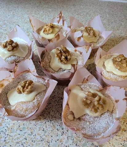 A white cupcake with a walnut on top.