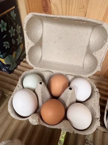 A box of eggs is sitting on a wooden table.