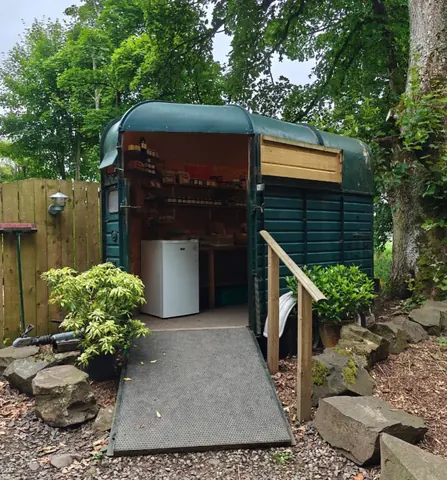 A green trailer with a white fridge and a table inside.