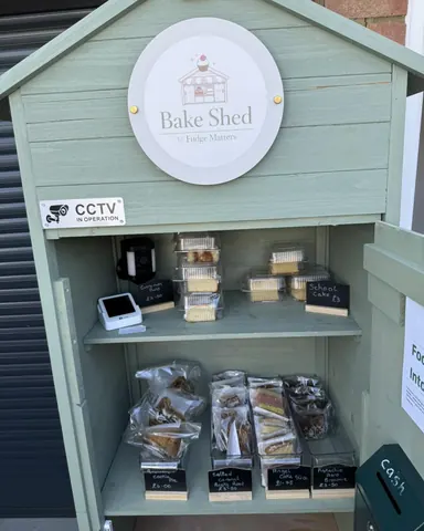A small green building with a sign that says "Baked Shed".