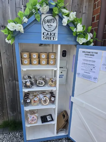 A blue shed with a sign that says "welcome to the cake shed".