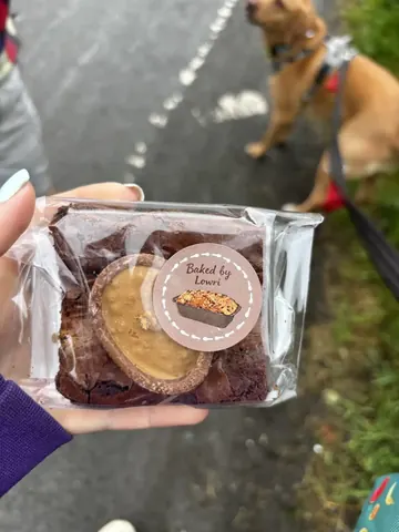 A person is holding a chocolate dessert in their hand.