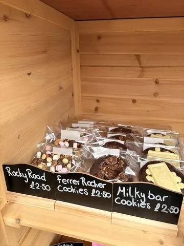 A display of various chocolates and cookies in a wooden case.