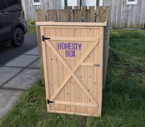 A wooden box with a purple sign on it.