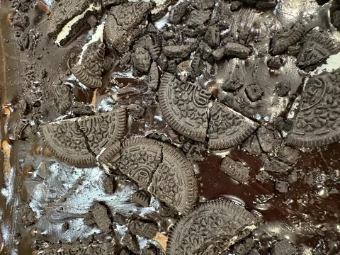 A chocolate cake with a crumbly texture and a few Oreo cookies on it.