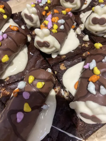A chocolate cake with white frosting and yellow sprinkles.