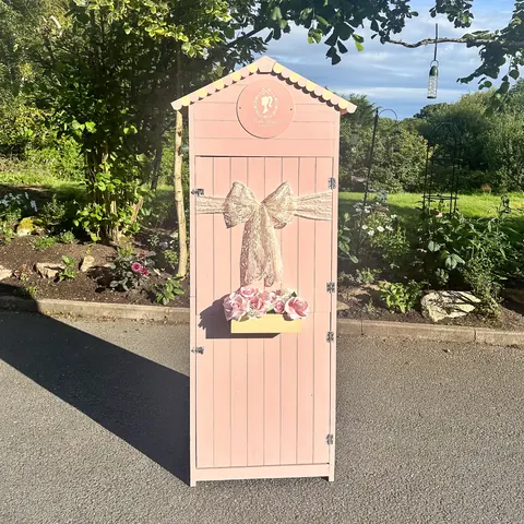 A pink shed with a bow on it.
