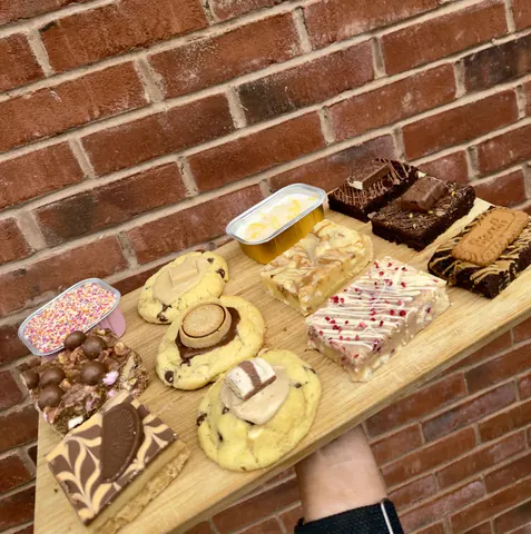 A wooden tray with a variety of desserts on it.