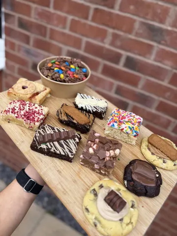A person is holding a tray with various desserts on it.