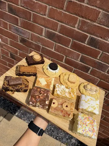A wooden tray with a variety of desserts on it.