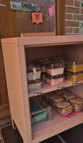 A pink shelf with a variety of food items on it.