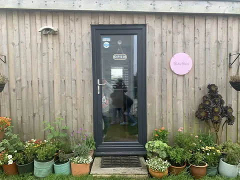 A wooden building with a pink sign on the door.