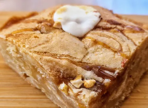 A piece of cake with white frosting and nuts on top.