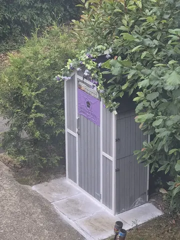 A small shed with a purple sign on it.
