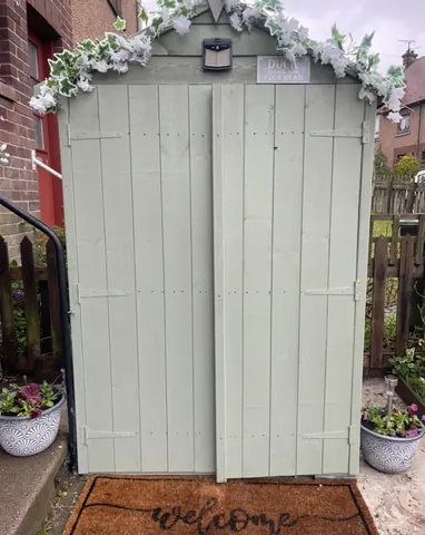 A green shed with a white door.