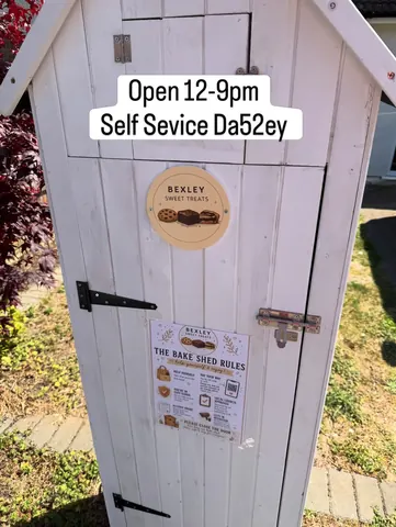 A white shed with a sign on it.
