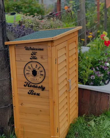 A wooden outhouse with a sign on it.
