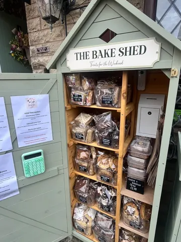 A small wooden structure with a sign that says "The Bakery Shed" and a display of baked goods inside.