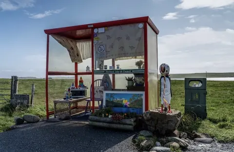 A red and white bus stop with a sign on the side.