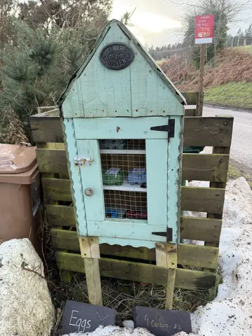 A small blue shed with a sign on it.