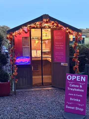 A small building with a neon sign that says "open" on the door.