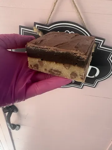 A person is holding a piece of chocolate cake.