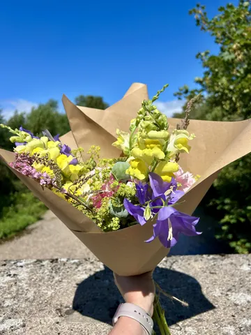 A bouquet of flowers in a brown paper bag.