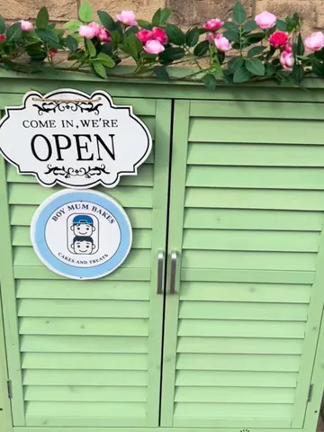 A sign that says "come in we're open" is on a green door.