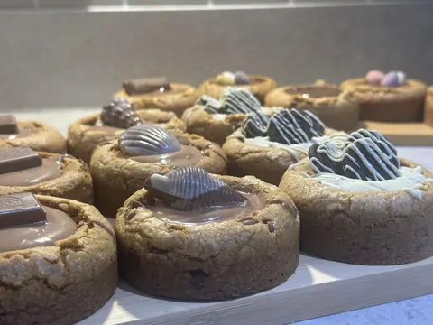 A wooden tray with a variety of cookies on it.