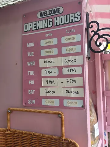 A pink sign with a clock on it.