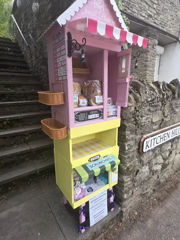 A pink and yellow food cart with a sign on the side.